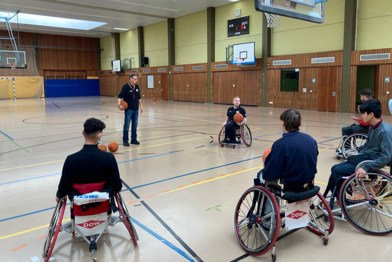 Trainer Paul Bowes und Spieler Jim Palmer erklären den Schülern Rollstuhlbasketball