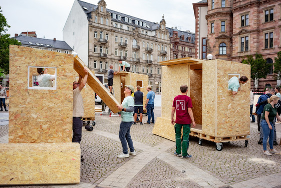 Fünf kleine Holzhäuschen, die Obdachlosen in Wiesbaden auf dem Weg zurück ins „normale“ Leben vorübergehend als Wohnstatt dienen sollen. Gebaut wurden sie von Mitarbeitenden der Commerz Real, der Immobilientochter der Commerzbank.