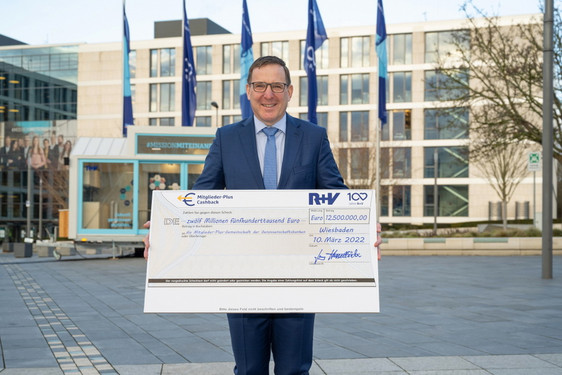 R+V-Vertriebschef Jens Hasselbächer mit einem symbolischen Cashback-Scheck von 12,5 Millionen Euro für die R+V-Mitglieder-Plus-Kunden