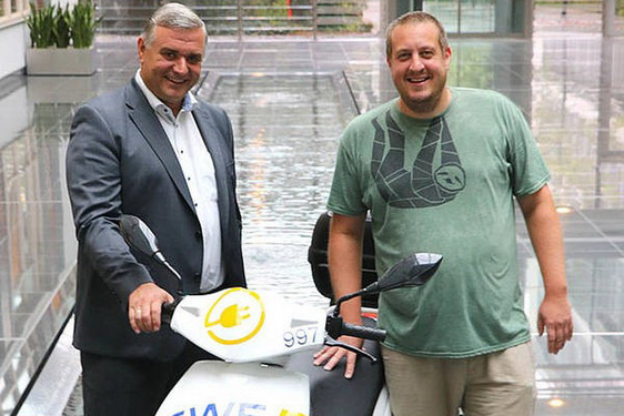 ESWE-Vorstandsmitglied Jörg Höhler (links) und Teamleiter Michael Weinand vom Stadtjugendring bei der Roller-Übergabe im Atrium von ESWE Versorgung.