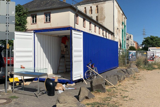In Wiesbaden-Biebrich eröffnet die Ausstellung „Biebrich und der Rhein“. In einem leuchtend blauen Container an der Rheinpromenade sind Bilder und Objekte rund um die Geschichte Biebrichs zu sehen.