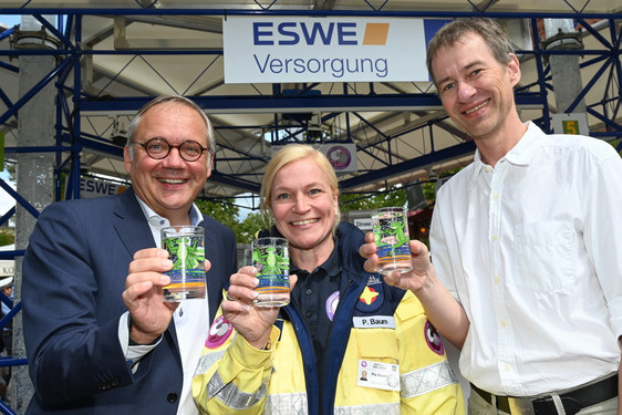 Ralf Schodlok (l., Vorstandsvorsitzender der ESWE Versorgungs AG), Pia Baum („Seelsorge in Notfällen“) und Designer Michael Spengler präsentieren auf der Rheingauer Weinwoche das Wasserglas 2019